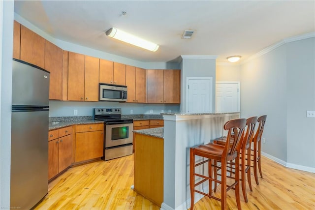 2502 Leon St Unit 305, Austin, TX 78705 - kitchen featuring stainless steel appliances, light wood-type flooring, a kitchen breakfast bar, brown cabinetry, and ornamental molding