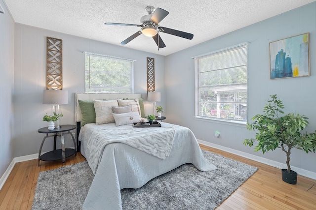 932 E 53 1/2 St, Austin, TX 78751 - bedroom with wood-type flooring, a textured ceiling, and a ceiling fan