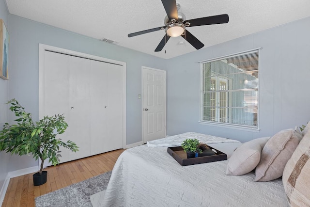 932 E 53 1/2 St, Austin, TX 78751 - bedroom with hardwood / wood-style flooring, a closet, a textured ceiling, and a ceiling fan