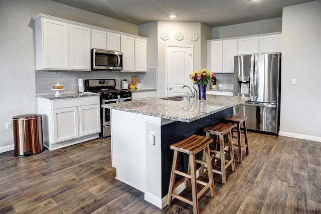 508 Bluffview Dr, Bastrop, TX 78602 - kitchen with stainless steel appliances, an island with sink, backsplash, dark wood-style floors, and white cabinetry
