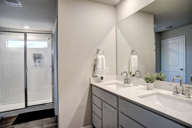 508 Bluffview Dr, Bastrop, TX 78602 - full bathroom featuring double vanity, a textured wall, a shower stall, and wood finished floors