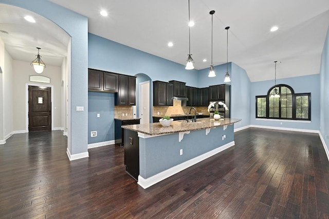 204 Lake Como Dr, Austin, TX 78734 - kitchen featuring arched walkways, light stone countertops, backsplash, dark wood-style floors, and a spacious island
