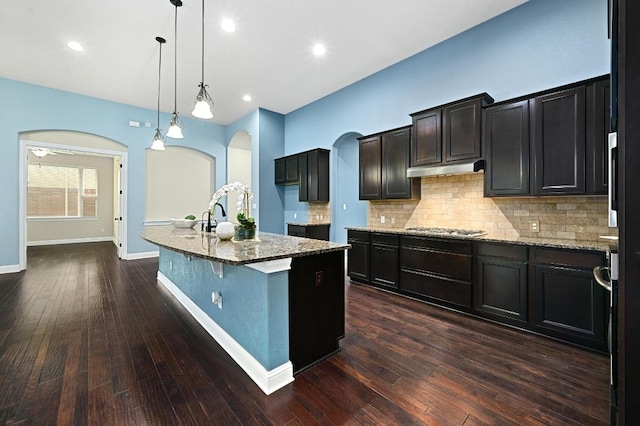 204 Lake Como Dr, Austin, TX 78734 - kitchen featuring arched walkways, stainless steel gas stovetop, light stone counters, decorative backsplash, and recessed lighting