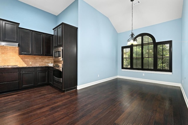 204 Lake Como Dr, Austin, TX 78734 - kitchen featuring appliances with stainless steel finishes, vaulted ceiling, backsplash, light stone counters, and dark wood-type flooring