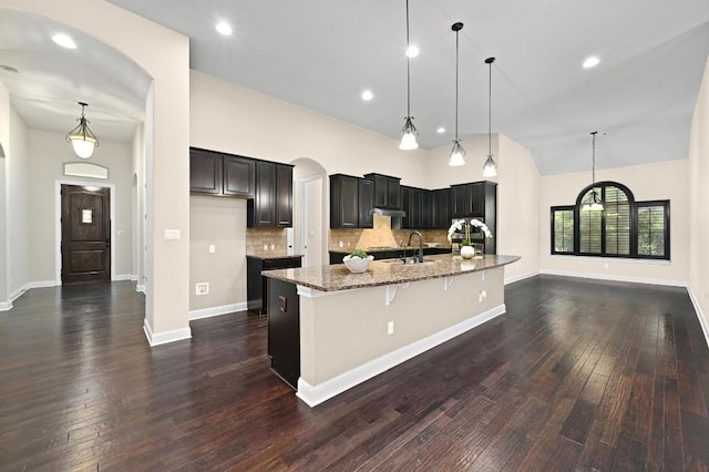 204 Lake Como Dr, Austin, TX 78734 - kitchen with light stone countertops, arched walkways, dark wood-style floors, backsplash, and a large island