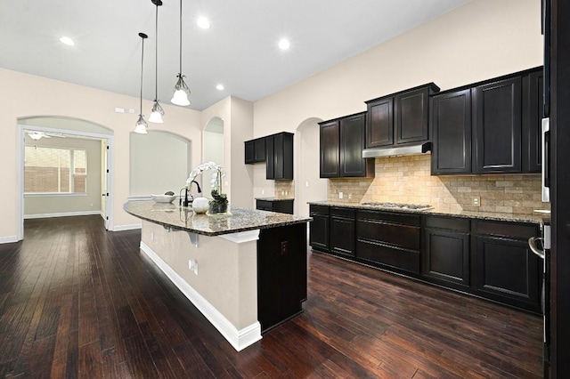 204 Lake Como Dr, Austin, TX 78734 - kitchen featuring arched walkways, stone countertops, stainless steel gas cooktop, decorative backsplash, and dark wood-type flooring