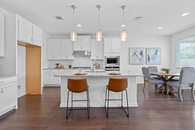 4409 Arques Ave, Round Rock, TX 78681 - kitchen with appliances with stainless steel finishes, under cabinet range hood, backsplash, white cabinetry, and recessed lighting