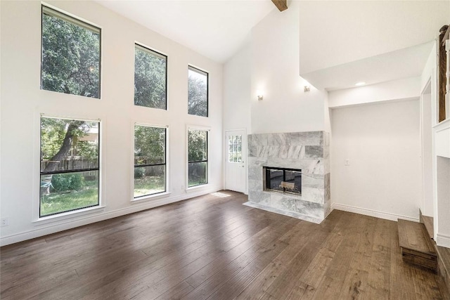 10703 Keystone Bnd, Austin, TX 78750 - unfurnished living room featuring a tiled fireplace, high vaulted ceiling, plenty of natural light, and wood finished floors