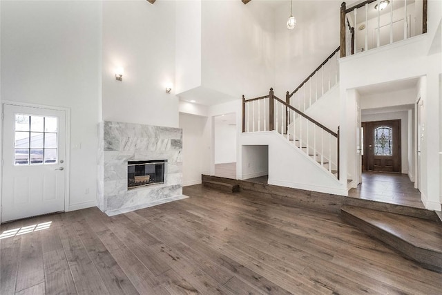 10703 Keystone Bnd, Austin, TX 78750 - unfurnished living room featuring a high ceiling, wood-type flooring, healthy amount of natural light, stairs, and a high end fireplace