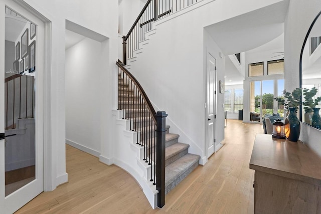 stairs with wood finished floors and a towering ceiling
