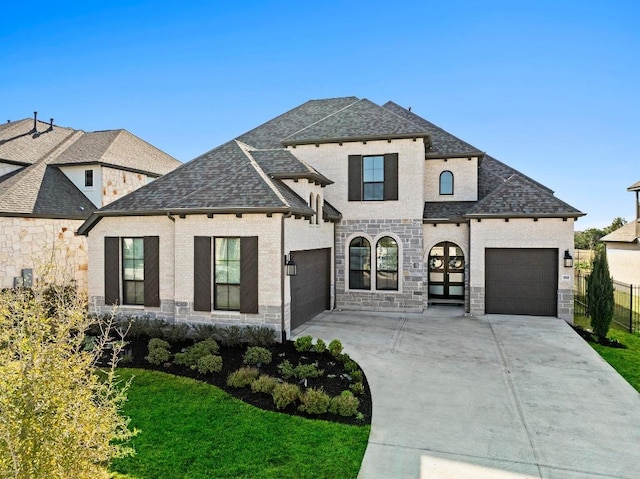 french country inspired facade with a garage, driveway, stone siding, and a front lawn