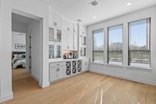 dining room featuring light wood-style flooring, recessed lighting, and a bar