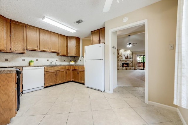 45 Oaks Pl, Lago Vista, TX 78645 - kitchen with white appliances, a ceiling fan, brown cabinets, a stone fireplace, and tasteful backsplash