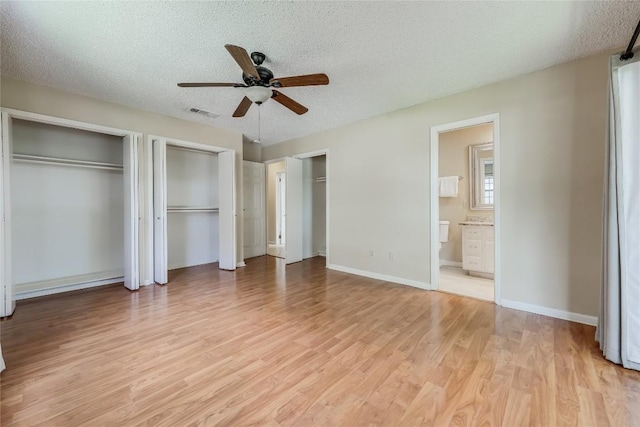 45 Oaks Pl, Lago Vista, TX 78645 - unfurnished bedroom with light wood finished floors, a textured ceiling, multiple closets, and ensuite bath