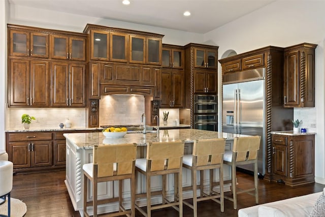 6000 Osceola Trl, Austin, TX 78738 - kitchen with stainless steel appliances, recessed lighting, tasteful backsplash, light stone counters, and a kitchen island with sink