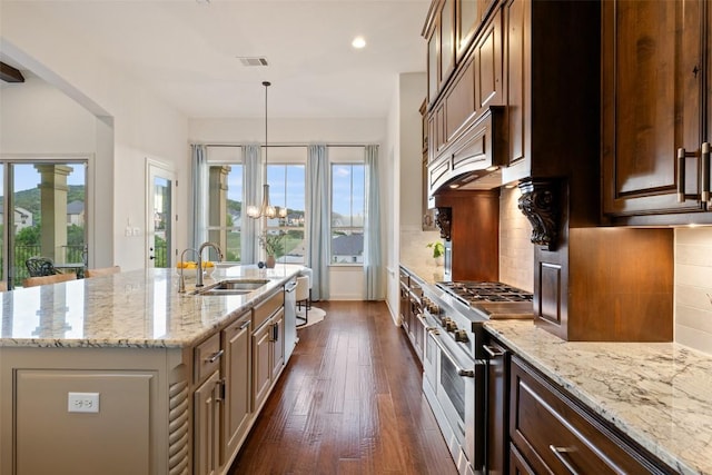 6000 Osceola Trl, Austin, TX 78738 - kitchen with stainless steel appliances, dark wood finished floors, a center island with sink, tasteful backsplash, and light stone countertops