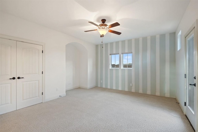 6000 Osceola Trl, Austin, TX 78738 - unfurnished bedroom with light colored carpet, arched walkways, a ceiling fan, wallpapered walls, and a closet