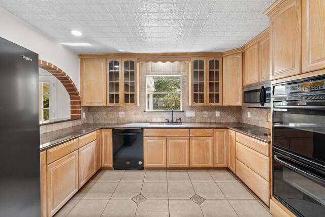 4217 Greystone Dr N, Austin, TX 78731 - kitchen with black appliances, light brown cabinetry, tasteful backsplash, and glass insert cabinets
