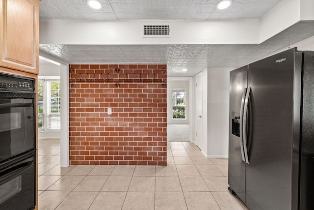 4217 Greystone Dr N, Austin, TX 78731 - kitchen with stainless steel fridge with ice dispenser, light tile patterned floors, recessed lighting, light brown cabinets, and brick wall