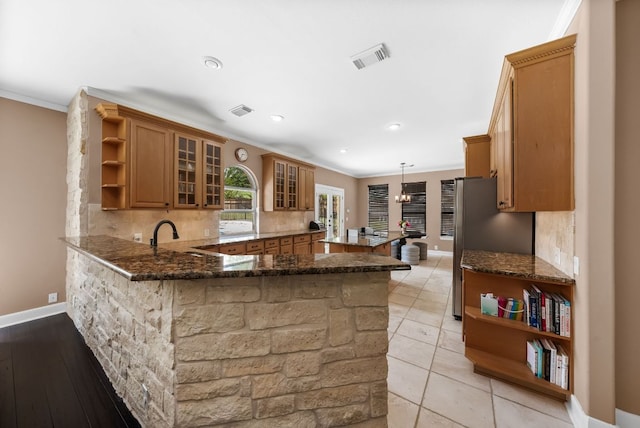 11606 Uplands Ridge Dr, Bee Cave, TX 78738 - kitchen with open shelves, a peninsula, brown cabinets, tasteful backsplash, and dark stone counters