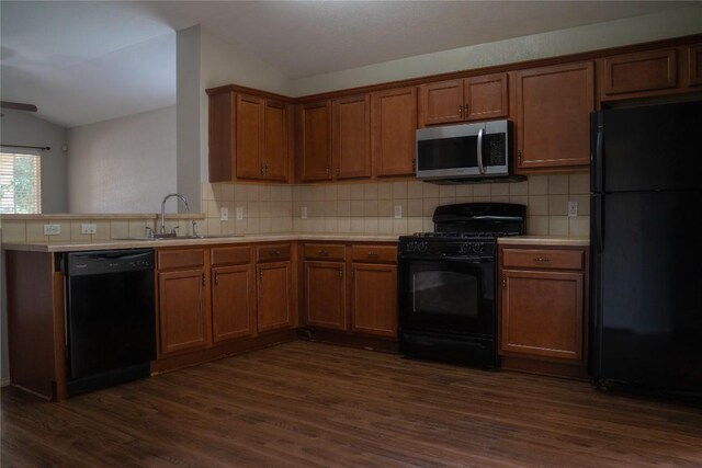 214 Wild Plum, San Marcos, TX 78666 - kitchen with black appliances, dark wood-style flooring, brown cabinetry, lofted ceiling, and tasteful backsplash