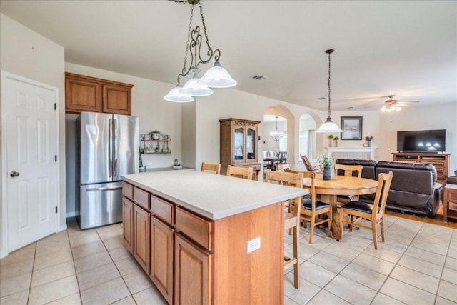 18717 Shoreless Dr, Pflugerville, TX 78660 - kitchen featuring freestanding refrigerator, arched walkways, light tile patterned floors, and open floor plan