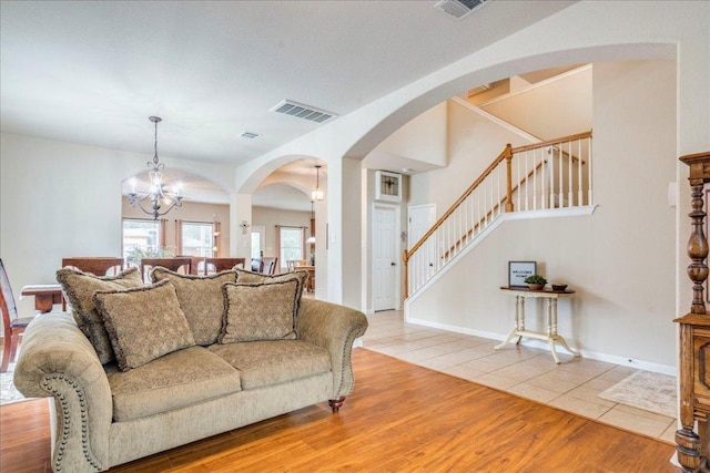 18717 Shoreless Dr, Pflugerville, TX 78660 - living room with stairs, arched walkways, a chandelier, and light tile patterned floors
