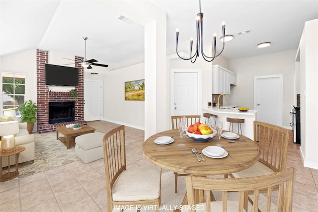 12922 Staton Dr, Austin, TX 78727 - dining space with ceiling fan, light tile patterned flooring, vaulted ceiling, a brick fireplace, and a chandelier