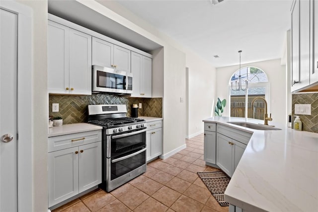 12922 Staton Dr, Austin, TX 78727 - kitchen with appliances with stainless steel finishes, decorative backsplash, a peninsula, light tile patterned floors, and decorative light fixtures