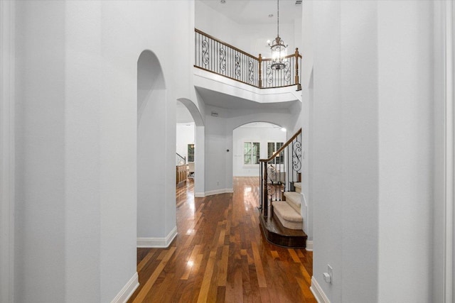13212 Coleto Creek Trl, Austin, TX 78732 - corridor with arched walkways, stairs, a chandelier, wood finished floors, and a high ceiling