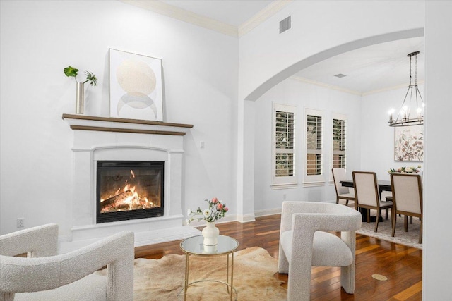 13212 Coleto Creek Trl, Austin, TX 78732 - living area with wood finished floors, arched walkways, a glass covered fireplace, crown molding, and a chandelier