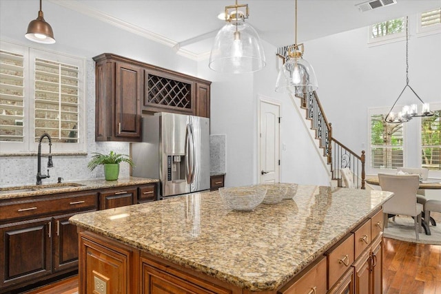 13212 Coleto Creek Trl, Austin, TX 78732 - kitchen featuring stainless steel fridge, a center island, dark wood-style flooring, light stone countertops, and crown molding