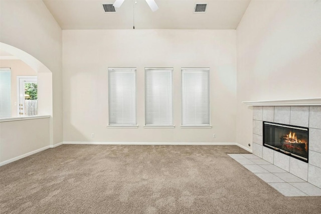 6710 Telluride Trl, Austin, TX 78749 - unfurnished living room with a ceiling fan, carpet floors, a tile fireplace, arched walkways, and baseboards
