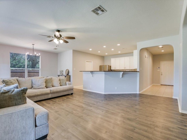 241 Sunnyside Dr, Kyle, TX 78640 - living room with a ceiling fan, light wood-type flooring, arched walkways, a chandelier, and recessed lighting