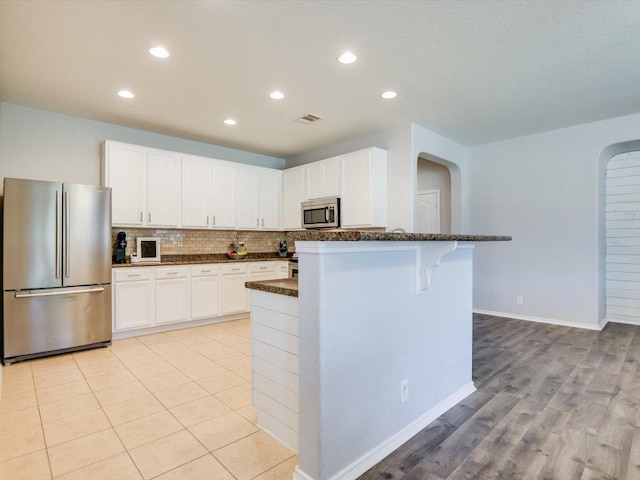 241 Sunnyside Dr, Kyle, TX 78640 - kitchen featuring appliances with stainless steel finishes, backsplash, white cabinetry, recessed lighting, and a kitchen breakfast bar