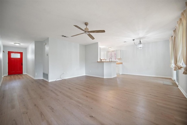 1009 Laurelleaf Dr, Pflugerville, TX 78660 - unfurnished living room with light wood-style floors, a ceiling fan, and a chandelier