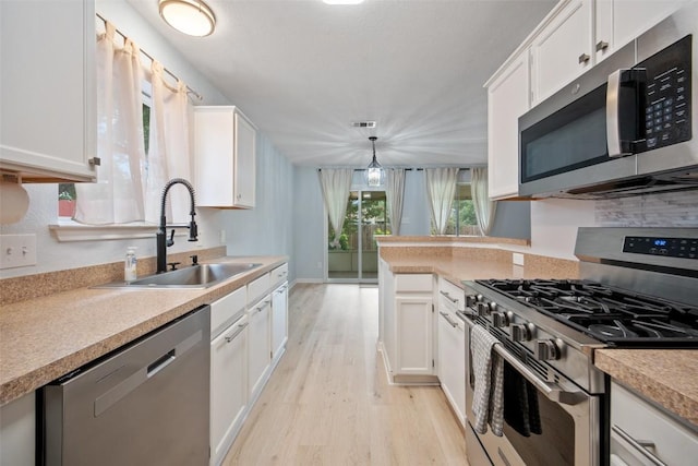 1009 Laurelleaf Dr, Pflugerville, TX 78660 - kitchen with stainless steel appliances, light wood finished floors, white cabinets, light countertops, and hanging light fixtures