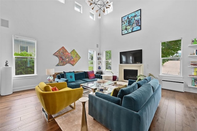 5904 Florencia Ln, Austin, TX 78724 - living room with a high ceiling, hardwood / wood-style flooring, a chandelier, a fireplace, and radiator heating unit