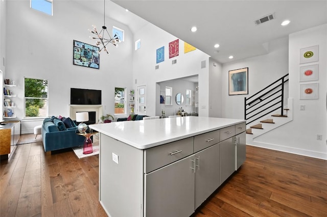 5904 Florencia Ln, Austin, TX 78724 - kitchen with gray cabinets, dark wood-type flooring, a towering ceiling, a kitchen island, and light countertops