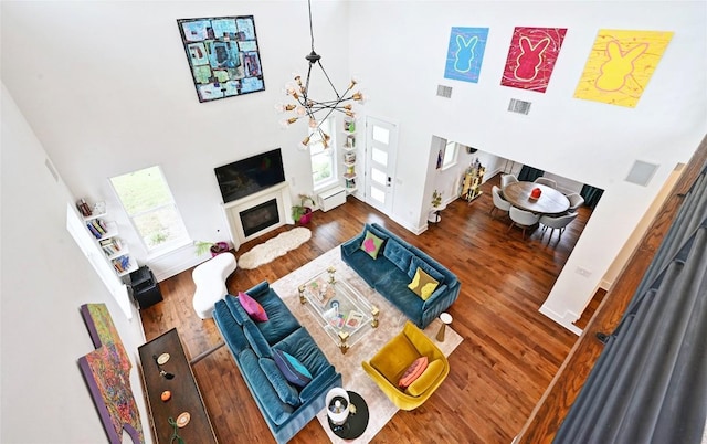 5904 Florencia Ln, Austin, TX 78724 - living room with a high ceiling, wood finished floors, a chandelier, and a glass covered fireplace