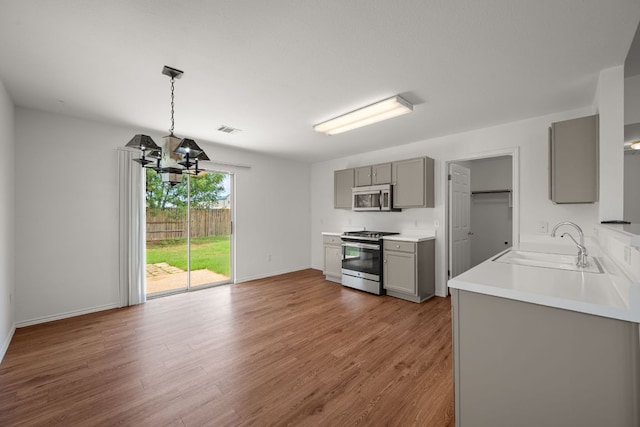 707 Eaglecreek Dr, Leander, TX 78641 - kitchen featuring gray cabinetry, appliances with stainless steel finishes, wood finished floors, a chandelier, and light countertops