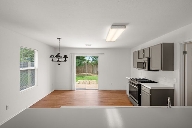 707 Eaglecreek Dr, Leander, TX 78641 - kitchen featuring appliances with stainless steel finishes, gray cabinetry, a chandelier, and light wood finished floors