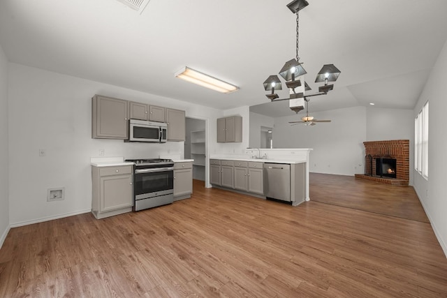 707 Eaglecreek Dr, Leander, TX 78641 - kitchen with stainless steel appliances, gray cabinets, open floor plan, a fireplace, and light countertops