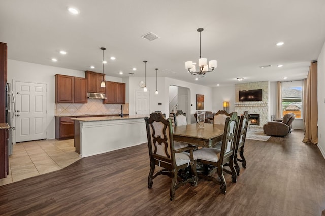 716 Madalin Rue Ct, Leander, TX 78641 - dining area with arched walkways, wood finished floors, recessed lighting, a stone fireplace, and a chandelier