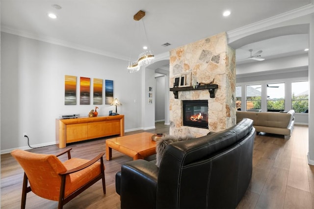2105 Peoria Dr, Leander, TX 78641 - living room featuring a stone fireplace, ornamental molding, wood finished floors, recessed lighting, and a chandelier