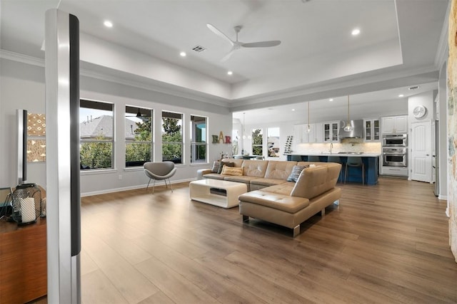 2105 Peoria Dr, Leander, TX 78641 - living room featuring a ceiling fan, crown molding, a raised ceiling, recessed lighting, and wood finished floors