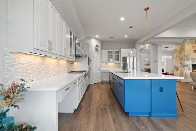2105 Peoria Dr, Leander, TX 78641 - kitchen with blue cabinetry, range hood, arched walkways, white cabinetry, and glass insert cabinets
