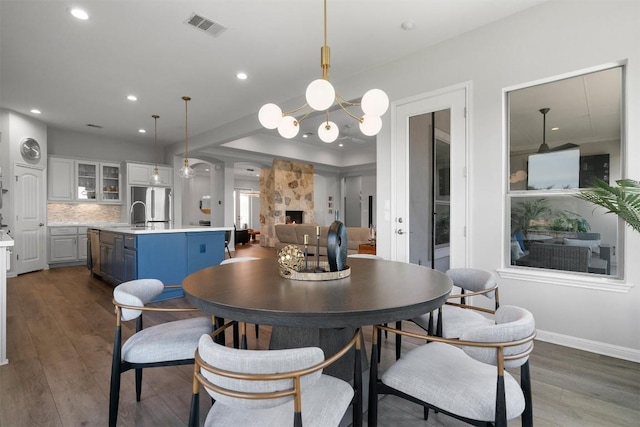 2105 Peoria Dr, Leander, TX 78641 - dining area featuring dark wood-type flooring, a stone fireplace, a chandelier, and recessed lighting