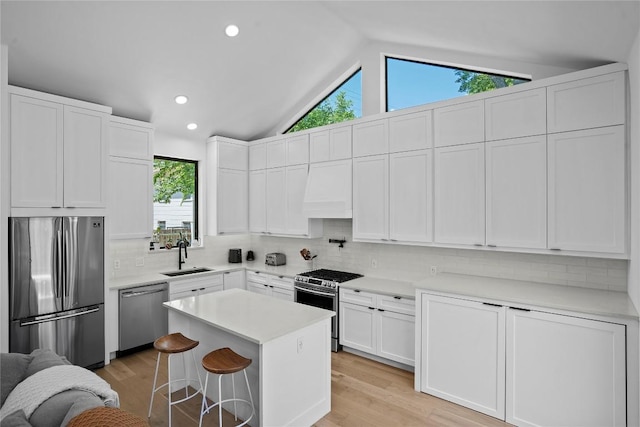 2216 Lindell Ave Unit 2, Austin, TX 78704 - kitchen featuring stainless steel appliances, custom exhaust hood, lofted ceiling, a kitchen breakfast bar, and white cabinets