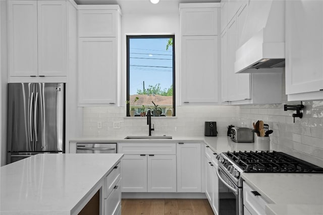 2216 Lindell Ave Unit 2, Austin, TX 78704 - kitchen with premium range hood, stainless steel appliances, white cabinetry, light wood-type flooring, and recessed lighting